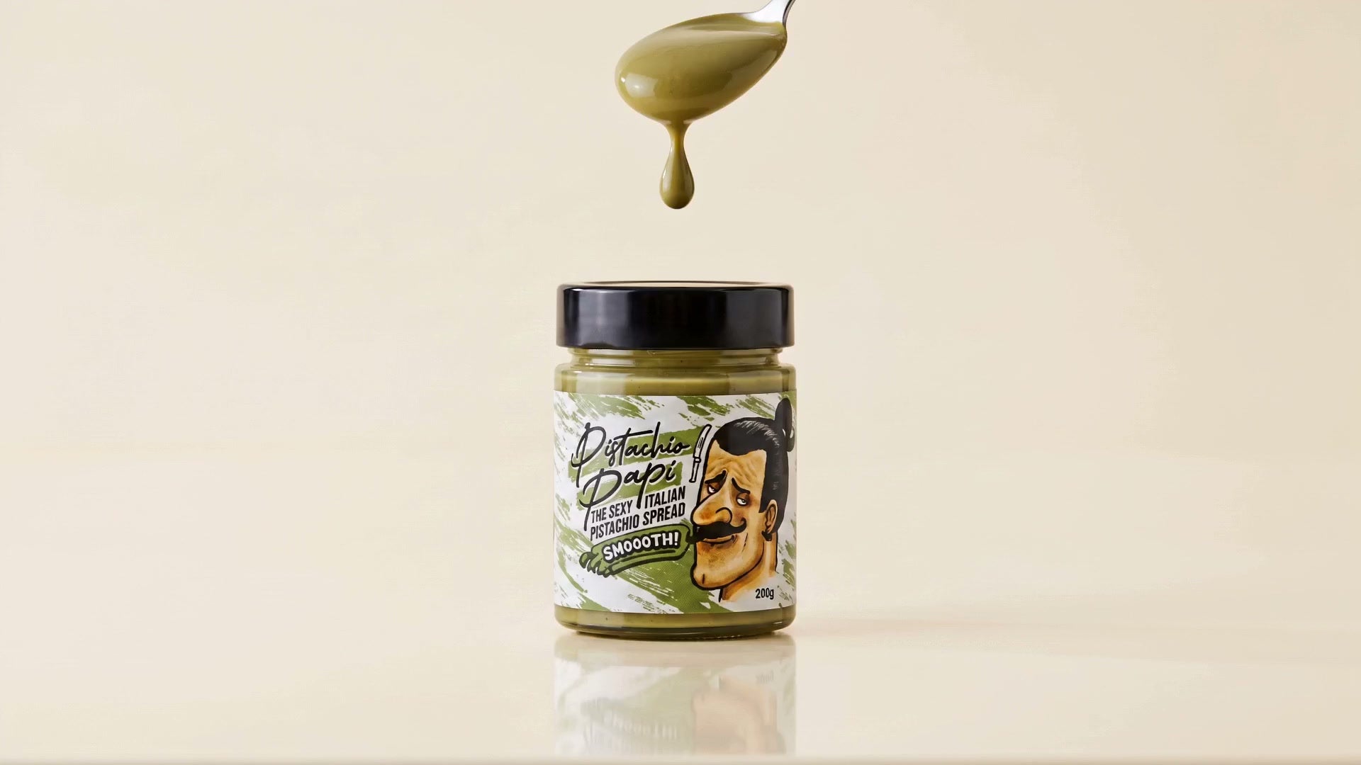 A spoon of Pistachio Papi dripping over the jar